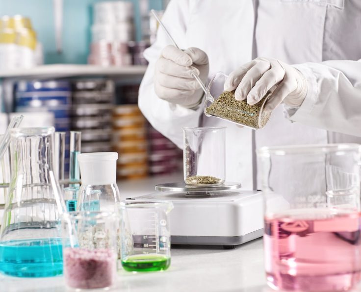 Medicine, pharmacy and cosmetology concept. Unrecognizable scientist manufacturing natural organic healthy cosmetics in laboratory, standing at desk with glass tubes filled with colored liquids